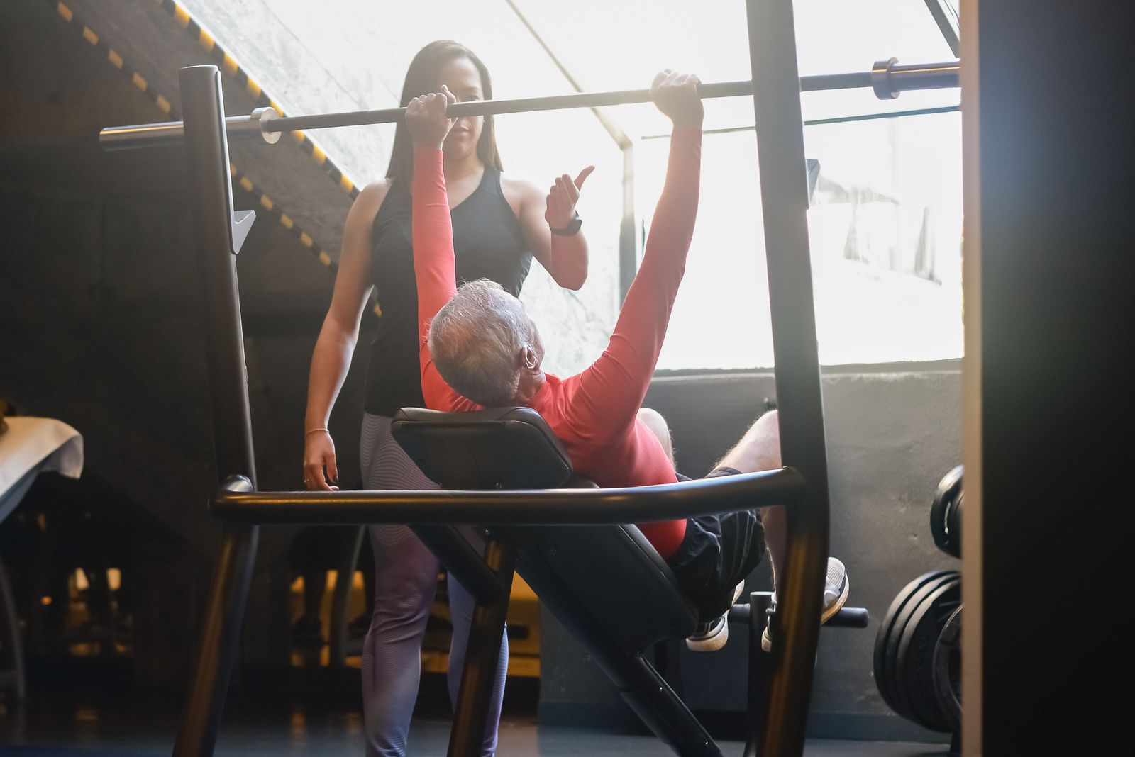 Physiotherapist guiding an elderly patient through supervised strength rehabilitation