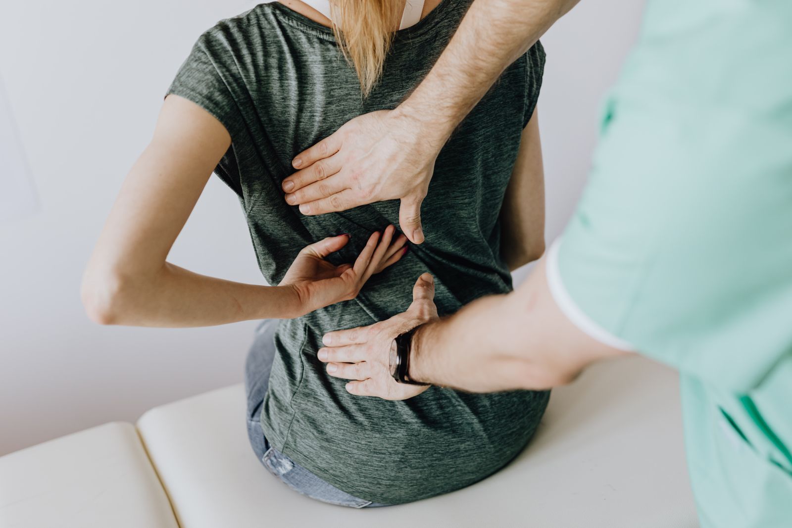 Physiotherapist performing a manual spinal assessment on a seated patient